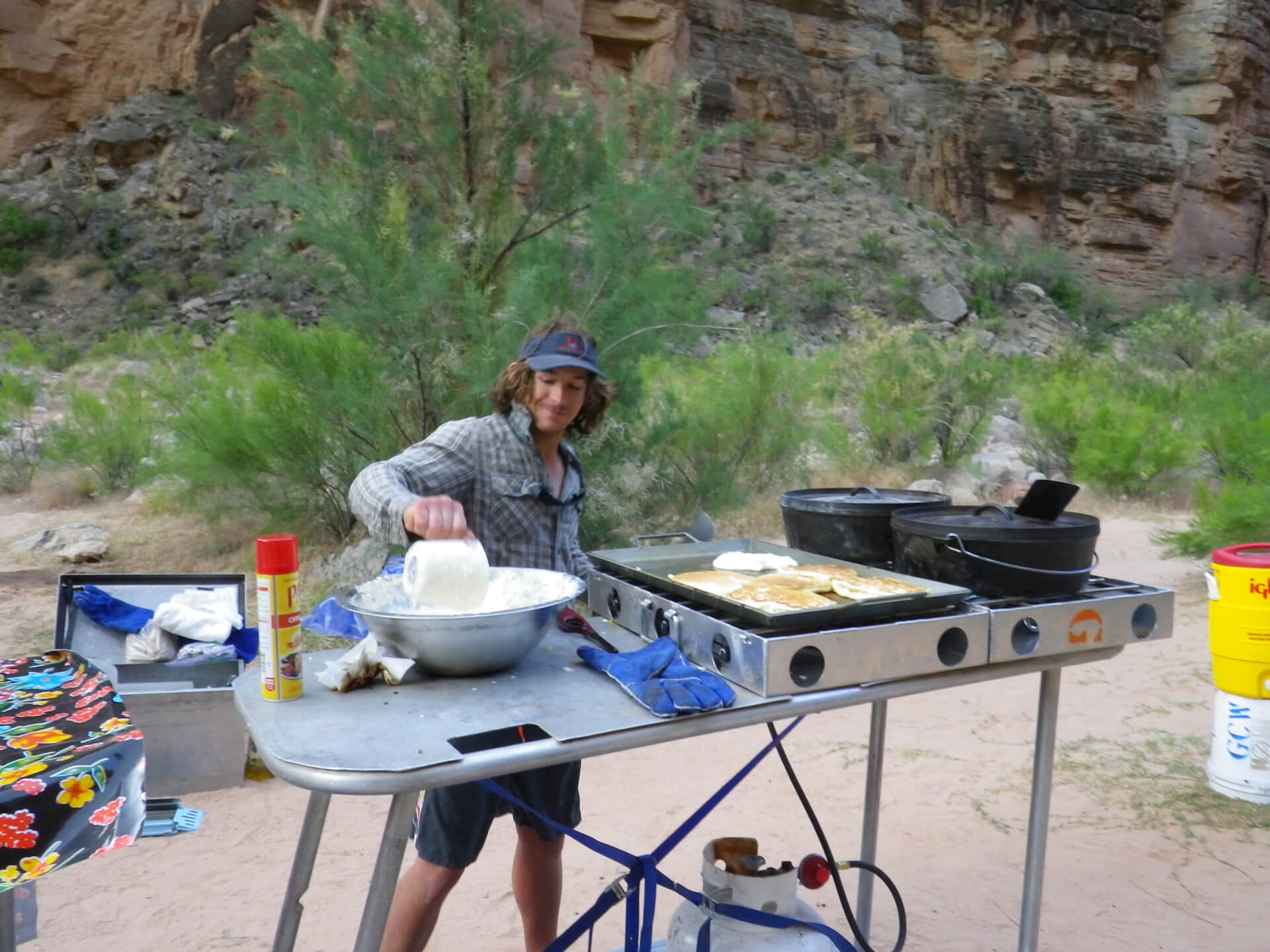 Zach, a Grand Canyon Whitewater guide, prepares pancakes in a river kitchen.