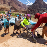 Volunteers helping a wheelchair woman get on the raft.