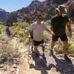 A man with a prosthetic leg gets assistance on a hike.