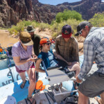 A group of people carry a woman in a wheelchair onto the raft.